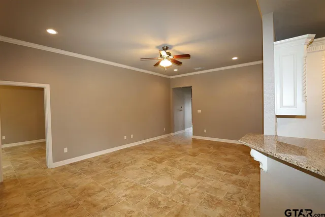 an empty room with a chandelier fan and windows