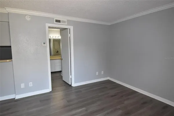 a view of an empty room with wooden floor and closet