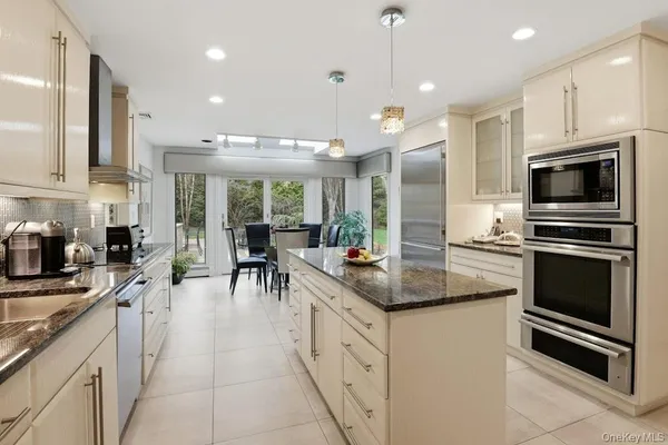a kitchen with kitchen island stainless steel appliances sink cabinets dining table and chairs