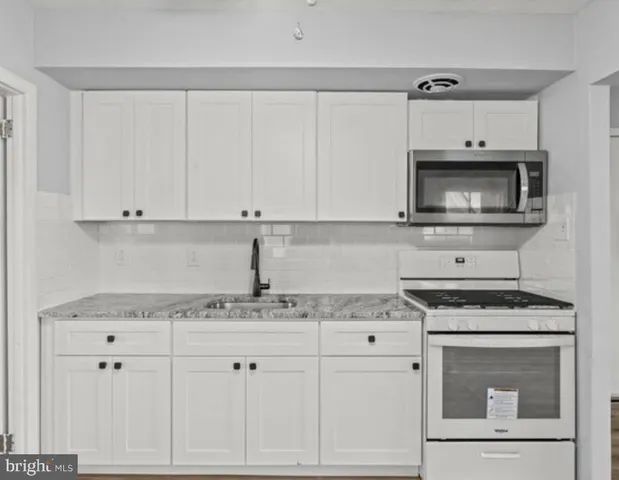 a kitchen with granite countertop white cabinets and white appliances