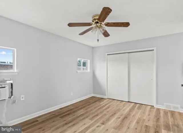 a view of empty room with wooden floor and fan