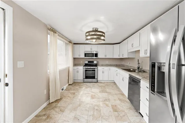 a kitchen with stainless steel appliances granite countertop a stove a sink and a refrigerator