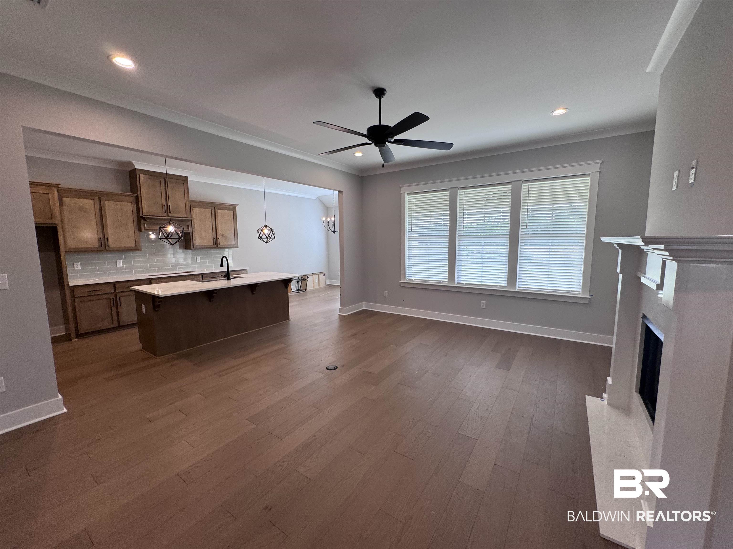 27371 Patch Pl Loop Daphne, AL 36526 - Photo 11 of 63 Kitchen featuring a ceiling fan, a center island with sink, backsplash, dark wood-style flooring, and a high end fireplace
