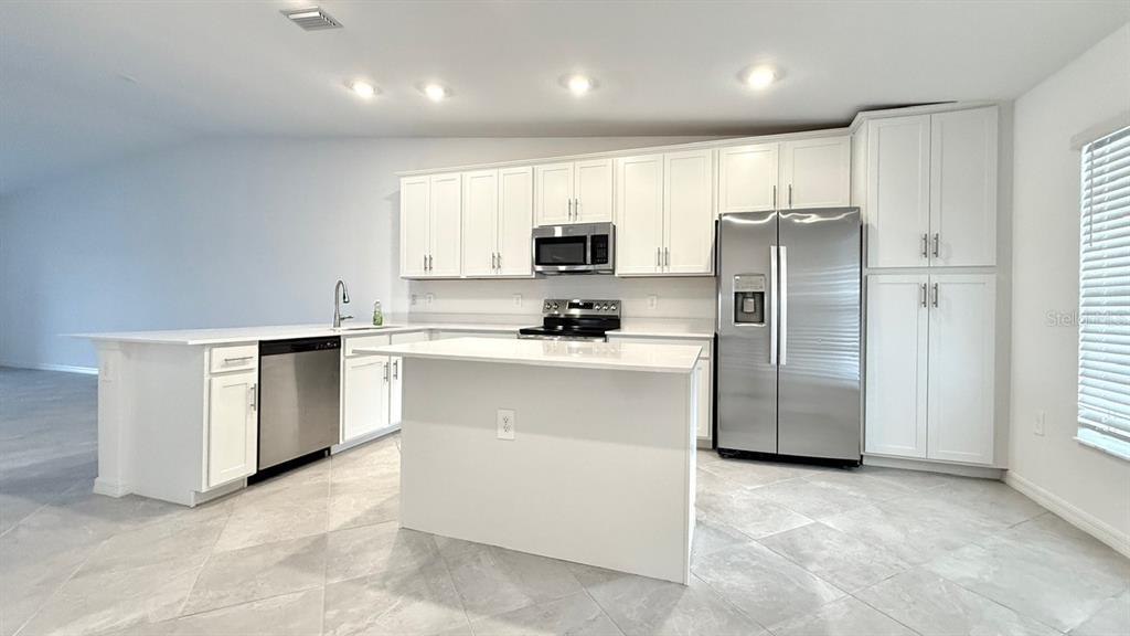 14261 Heritage Landing Boulevard, Unit 1621 Punta Gorda, FL 33955 - Photo 7 of 55 a kitchen with a refrigerator a microwave and white cabinets