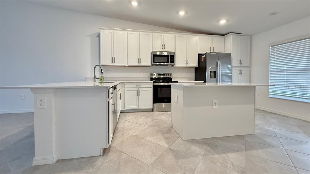 14261 Heritage Landing Boulevard, Unit 1621 Punta Gorda, FL 33955 - Photo 8 of 55 a kitchen with stainless steel appliances granite countertop a refrigerator oven a sink a stove and white cabinets