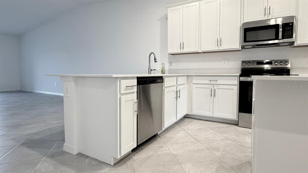 14261 Heritage Landing Boulevard, Unit 1621 Punta Gorda, FL 33955 - Photo 10 of 55 a kitchen with stainless steel appliances granite countertop a refrigerator and a stove top oven