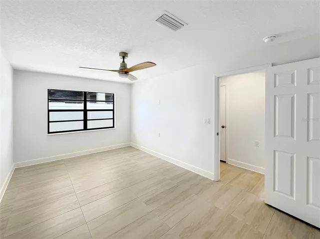 an empty room with windows and ceiling fan