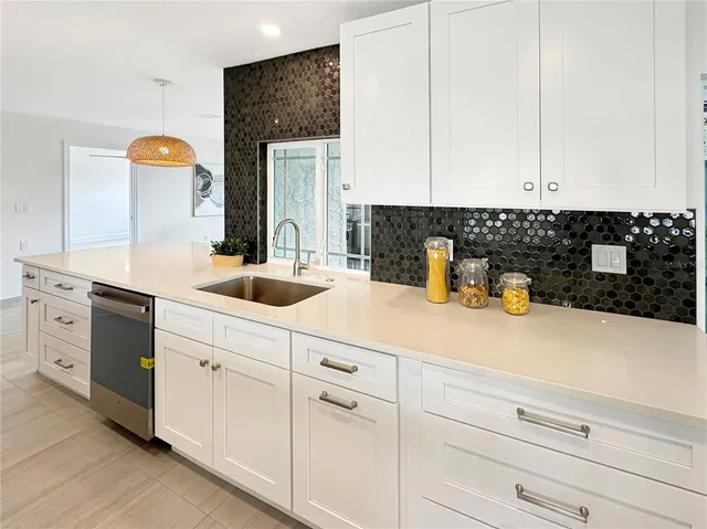 a kitchen with white cabinets and sink