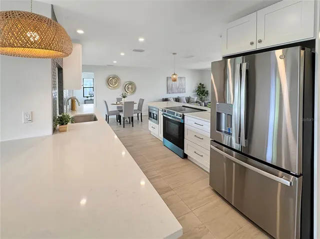 a kitchen with stainless steel appliances granite countertop a refrigerator a oven a sink and a dining table