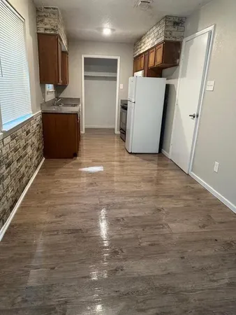 a view of a refrigerator in kitchen and an empty room