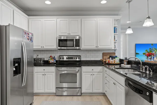 a kitchen with stainless steel appliances granite countertop a sink a stove a refrigerator and cabinets