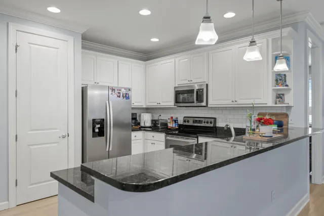 a kitchen with stainless steel appliances granite countertop a refrigerator a stove a sink a microwave and island