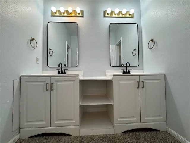 a bathroom with double vanity and a mirror