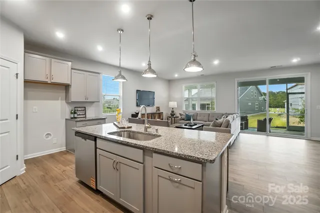 a kitchen with a sink a center island a counter top space and living room view