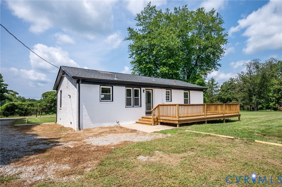 White brick exterior with black trim, wood deck, a