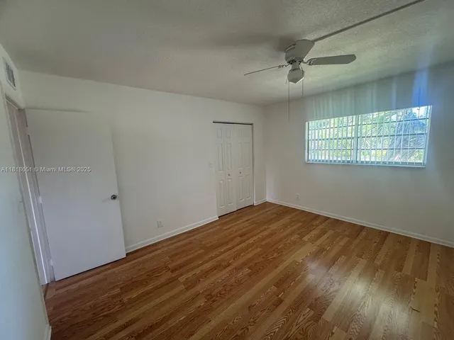 a view of empty room with wooden floor and fan