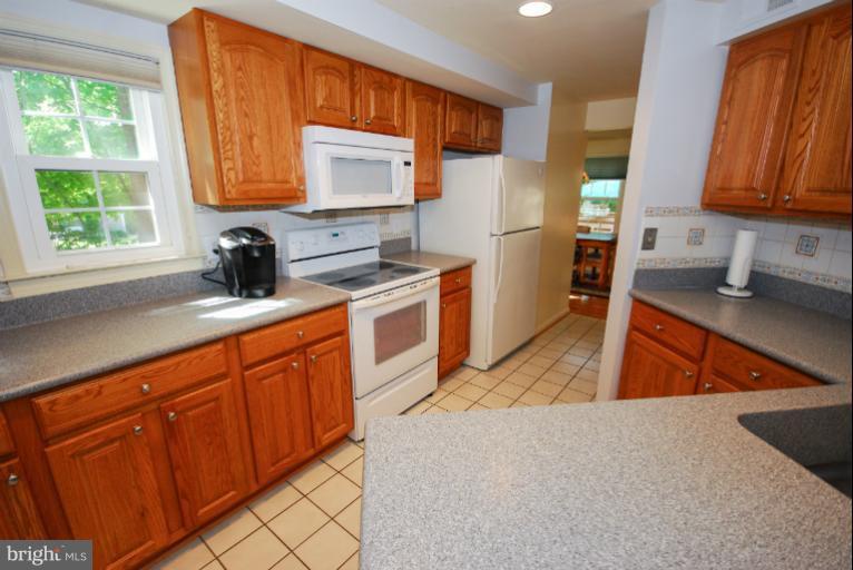 1503 Deer Point Way Reston, VA 20194 - Photo 3 of 21 a kitchen with stainless steel appliances granite countertop wooden cabinets a stove a sink a washer and dryer