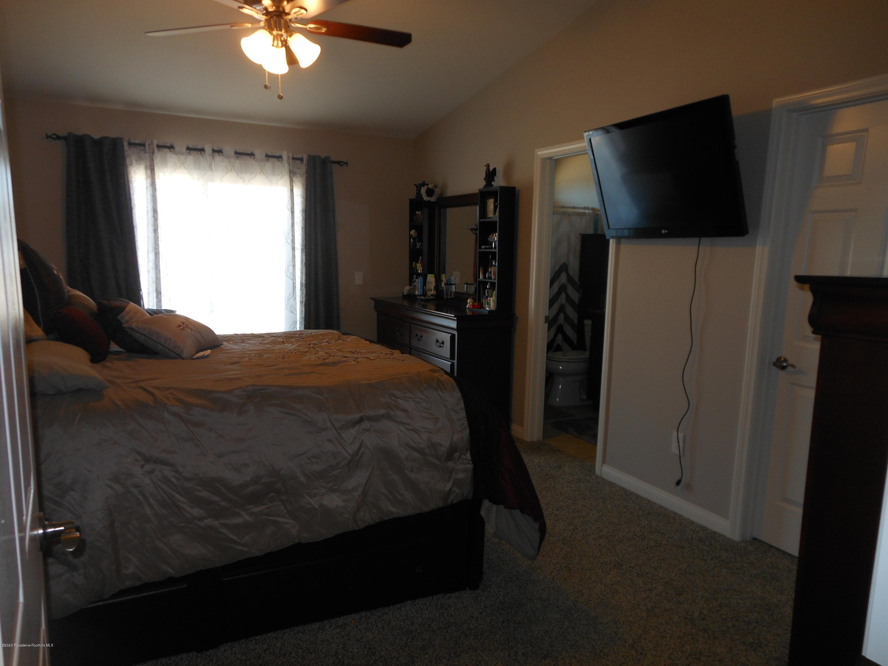14806 Cheyenne Road Apple Valley, CA 92307 - Photo 14 of 15 a bedroom with a bed and a flat tv screen in it