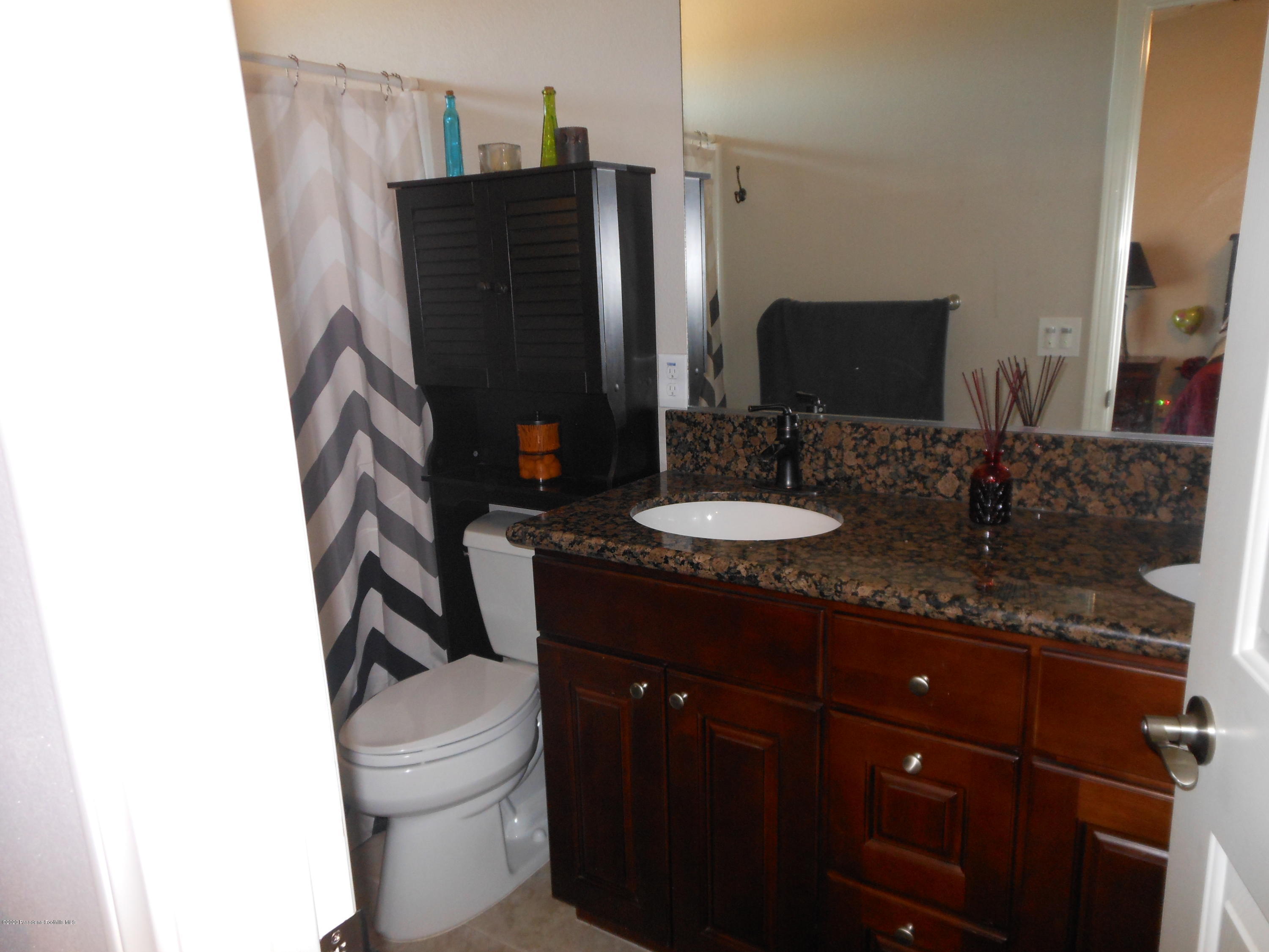 14806 Cheyenne Road Apple Valley, CA 92307 - Photo 10 of 15 a bathroom with a granite countertop sink toilet and mirror