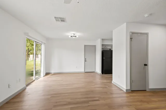 a view of an empty room with wooden floor and a window