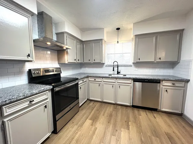 a kitchen with granite countertop a sink cabinets and stainless steel appliances