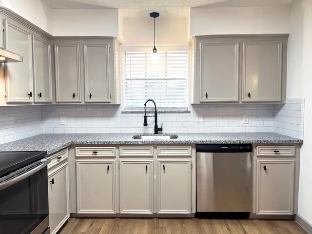 a kitchen with white cabinets and sink
