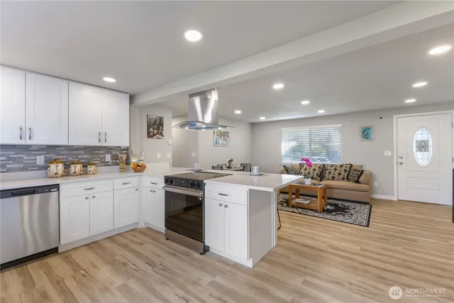a large white kitchen with stainless steel appliances granite countertop a stove and a sink