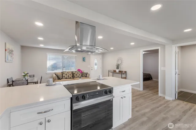 a kitchen that has a lot of white cabinets and stainless steel appliances