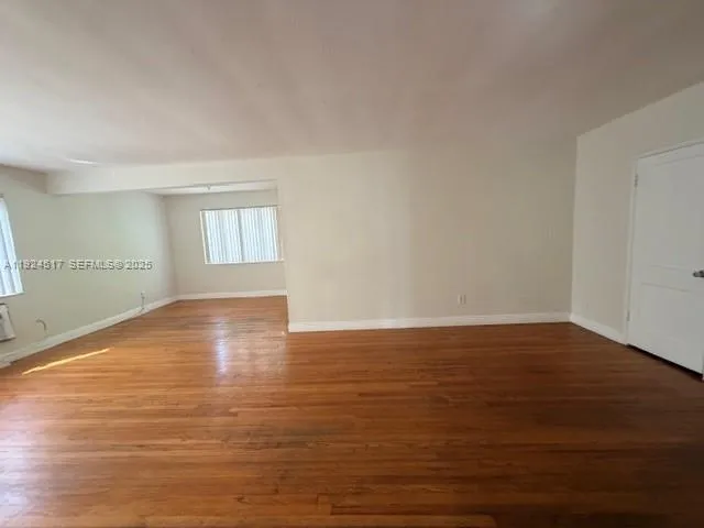 a view of empty room with window and wooden floor