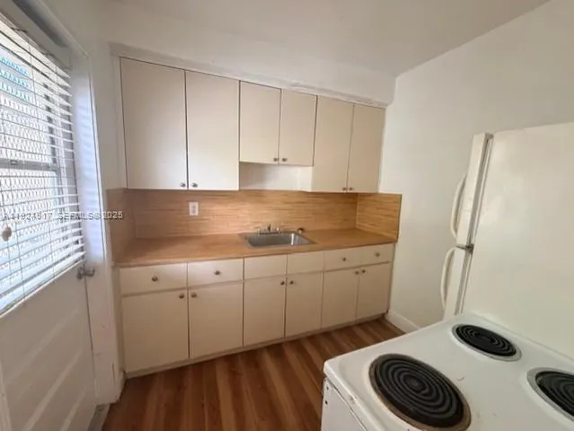 a kitchen with a refrigerator and white cabinets