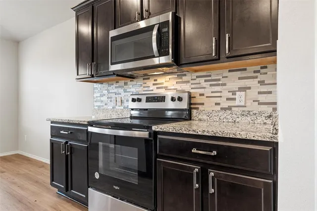 a kitchen with granite countertop a sink stove refrigerator and cabinets