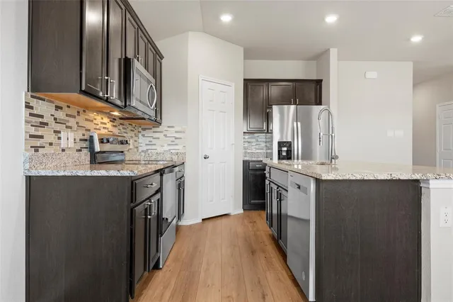 a kitchen with stainless steel appliances granite countertop a stove refrigerator and a microwave