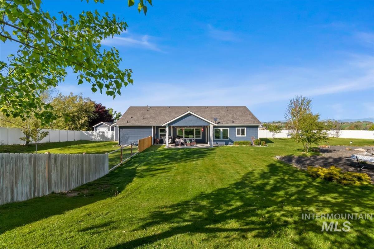 15015 Leon Lane Caldwell, ID 83607 - Photo 32 of 44 Expansive rear yard featuring a manicured lawn, a covered patio, and a dedicated fire pit area