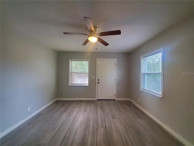 a view of empty room with wooden floor and fan