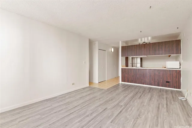 a view of kitchen and empty room with wooden floor