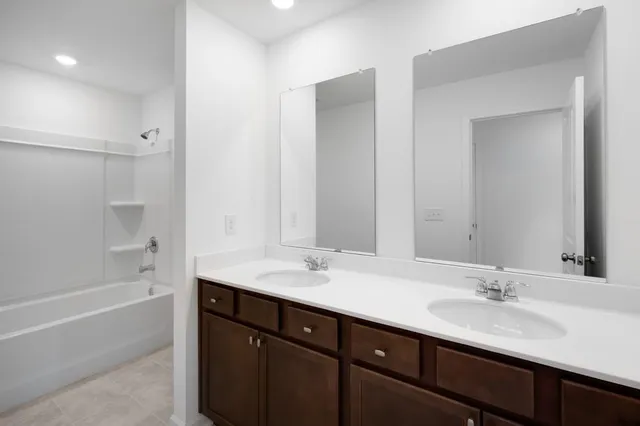 a bathroom with a sink double vanity granite tub shower and a mirror