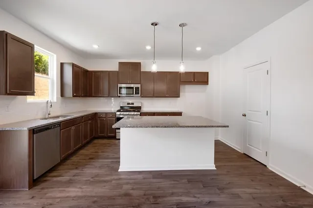 a kitchen with stainless steel appliances granite countertop a sink a stove a microwave a sink a refrigerator and a window