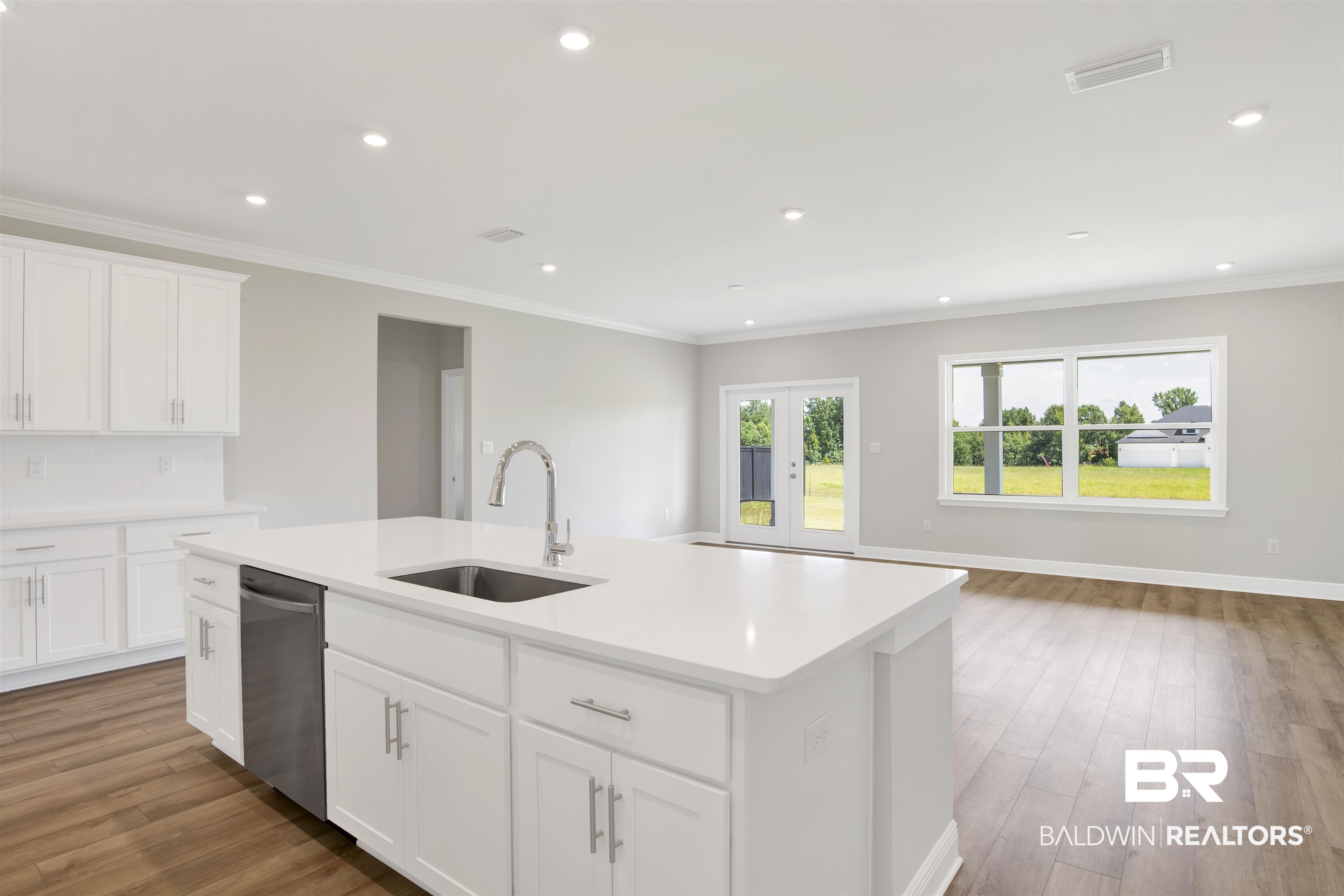 23852 Lafite Circle Daphne, AL 36526 - Photo 6 of 30 Kitchen with ornamental molding, wood finished floors, an island with sink, stainless steel dishwasher, and light countertops
