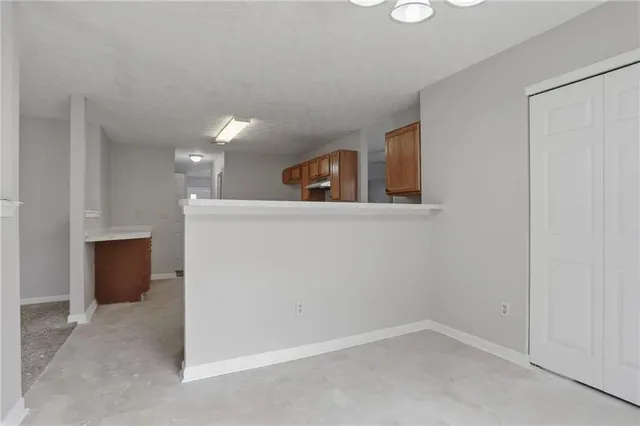 an empty room with kitchen view and wooden floor