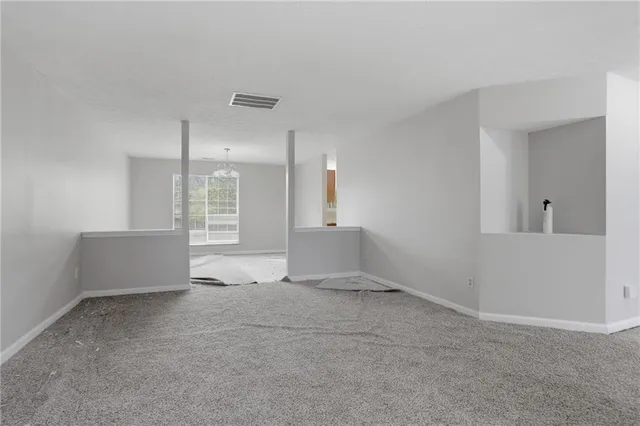 a view of an empty room with kitchen and a window