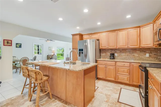 a kitchen with stainless steel appliances granite countertop a table chairs sink and cabinets