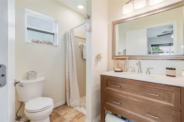 a bathroom with a granite countertop toilet sink and mirror