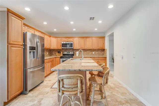 a kitchen with stainless steel appliances granite countertop a refrigerator and a stove top oven
