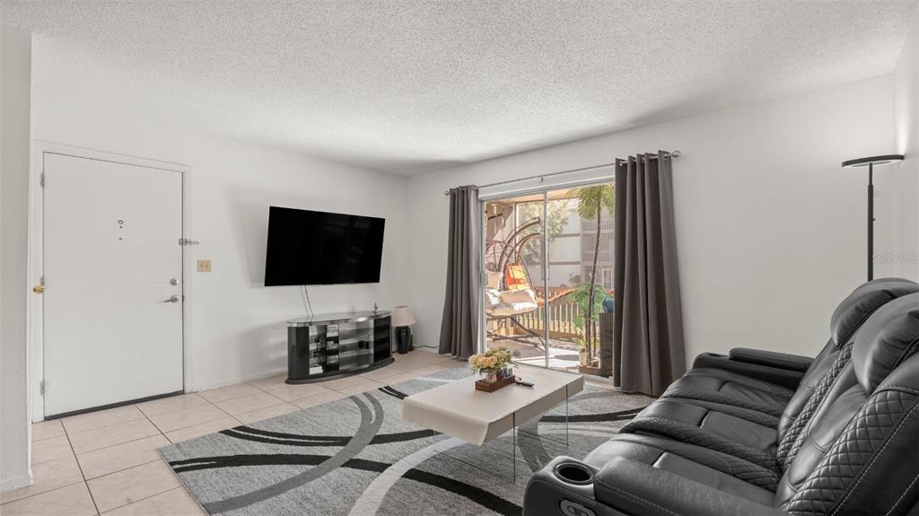 6519 West Newberry Road, Unit 912 Gainesville, FL 32605 - Photo 11 of 47 a living room with furniture a flat screen tv and a large window