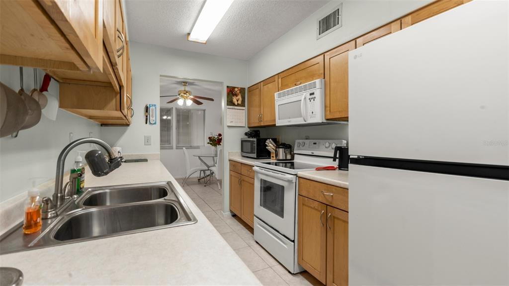 6519 West Newberry Road, Unit 912 Gainesville, FL 32605 - Photo 19 of 47 a kitchen with a sink a refrigerator and cabinets