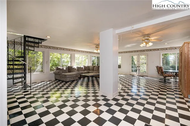 a living room with a black white checkered floor with a gaming machine and dining chairs