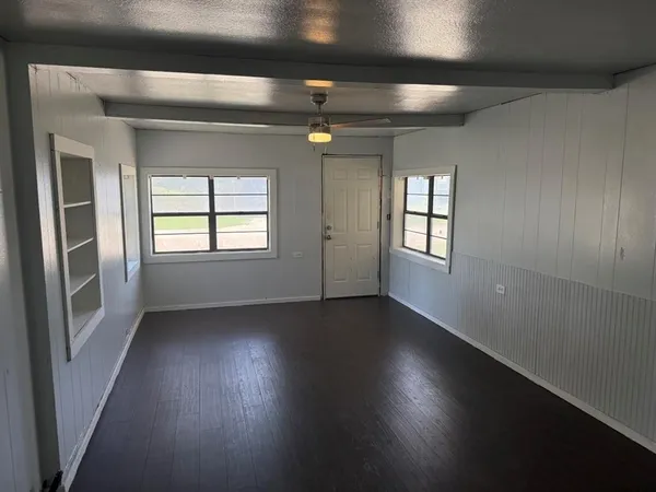 an empty room with wooden floor closet and windows