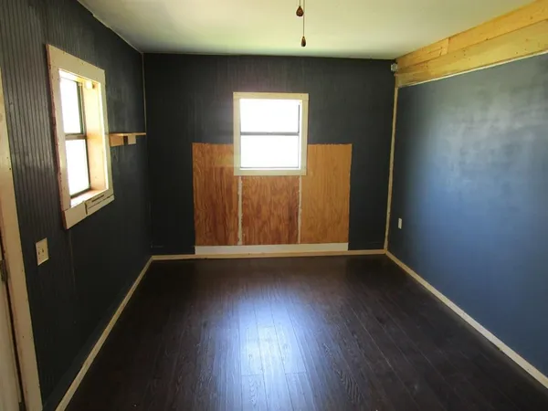 an empty room with wooden floor and a ceiling fan