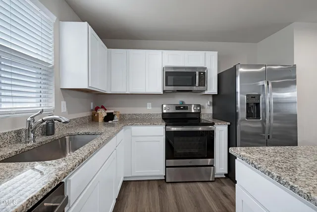a kitchen with granite countertop a sink stove and refrigerator