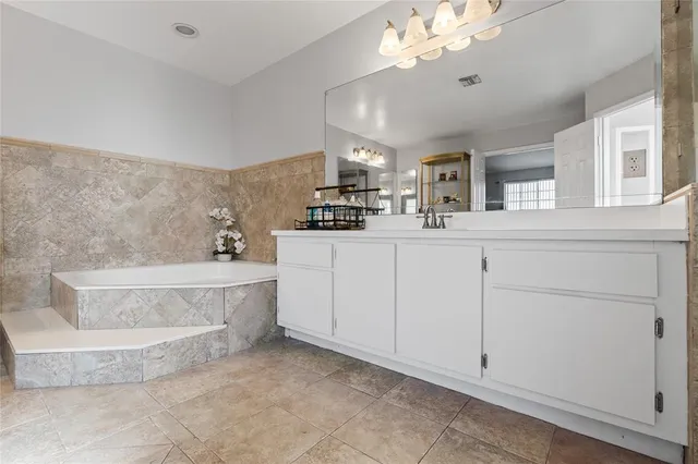 a spacious bathroom with a double vanity sink a mirror a bathtub and vanity